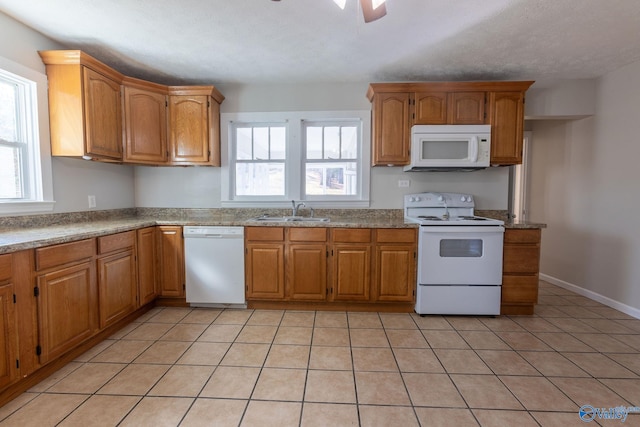 kitchen featuring plenty of natural light, sink, light tile patterned flooring, and white appliances