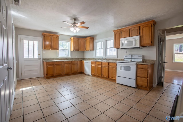 kitchen featuring ceiling fan, sink, a textured ceiling, white appliances, and light tile patterned floors