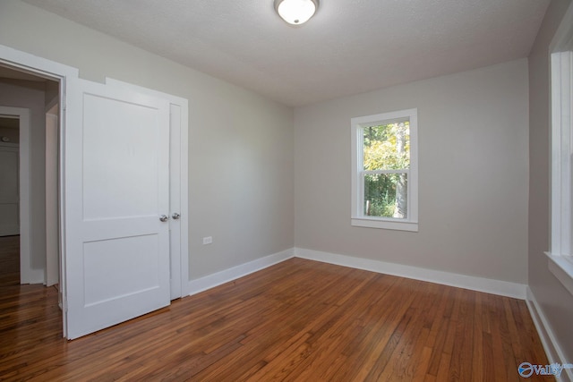 empty room featuring a textured ceiling and dark hardwood / wood-style floors