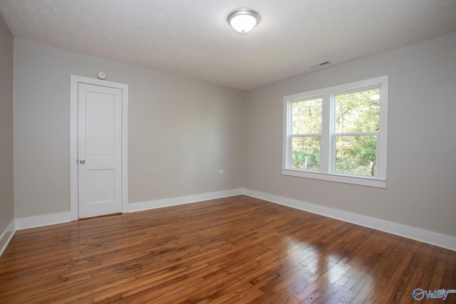 unfurnished room featuring hardwood / wood-style floors and a textured ceiling