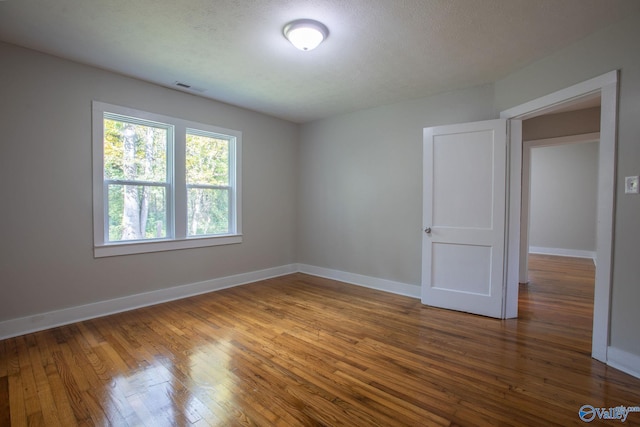 empty room featuring a textured ceiling and hardwood / wood-style flooring