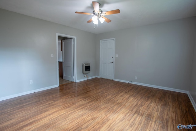 unfurnished room featuring heating unit, ceiling fan, and dark hardwood / wood-style floors