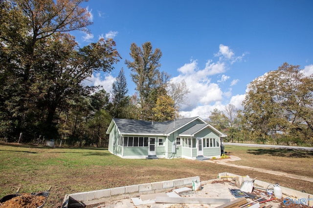 rear view of house with a yard and a sunroom