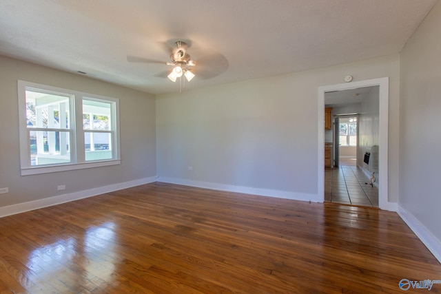 spare room with dark hardwood / wood-style floors, ceiling fan, and a wealth of natural light