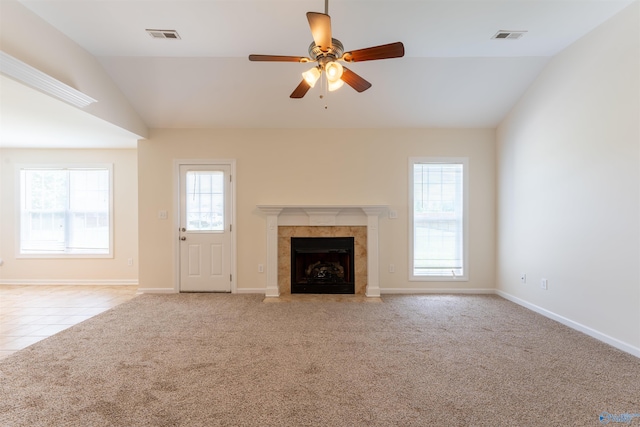 unfurnished living room with lofted ceiling, a wealth of natural light, light carpet, and a tiled fireplace