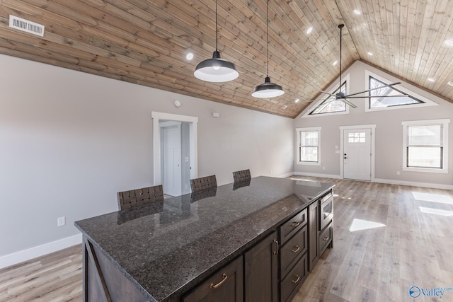 kitchen featuring pendant lighting, ceiling fan, wooden ceiling, and dark stone counters