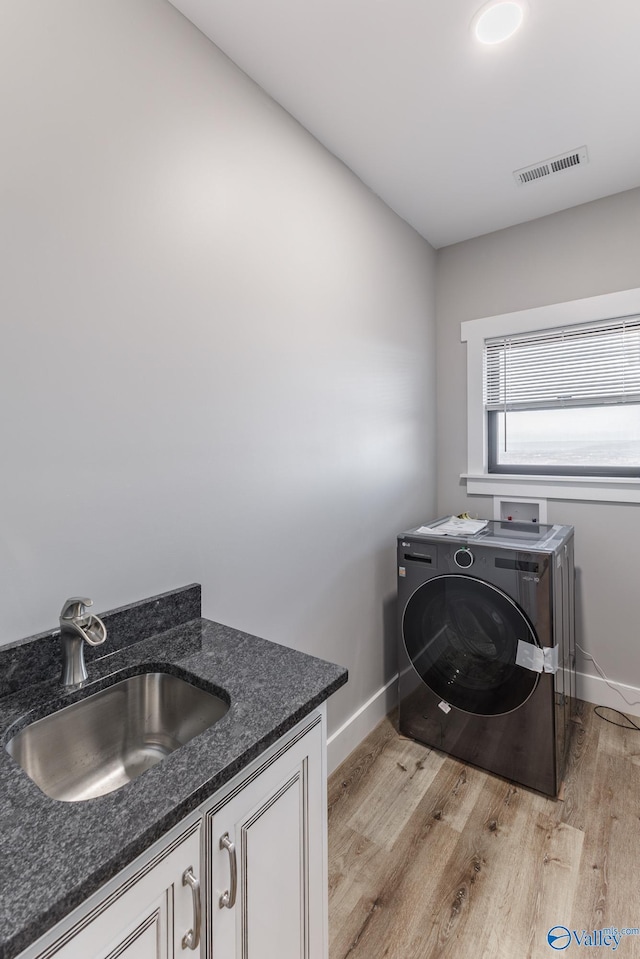 laundry area featuring cabinets, sink, washer / clothes dryer, and light hardwood / wood-style flooring