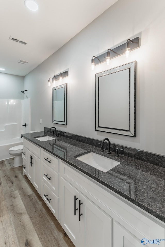 full bathroom with shower / tub combination, vanity, wood-type flooring, and toilet