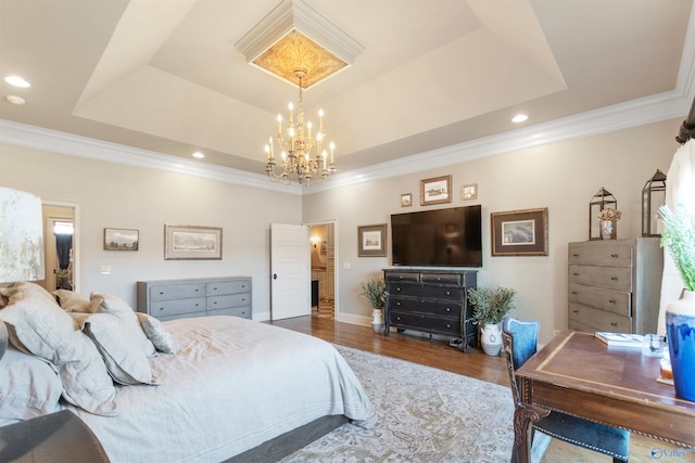 bedroom with a tray ceiling, ornamental molding, wood-type flooring, and an inviting chandelier