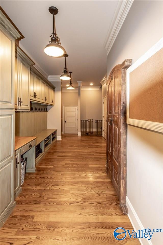 mudroom featuring ornamental molding, light wood-style flooring, and baseboards