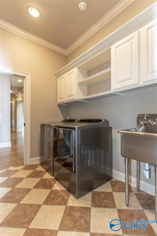 laundry room with washing machine and clothes dryer, cabinets, and ornamental molding