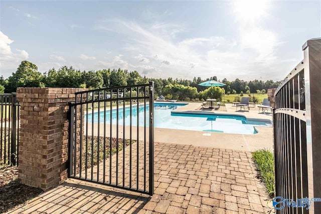 community pool featuring a gate, fence, and a patio