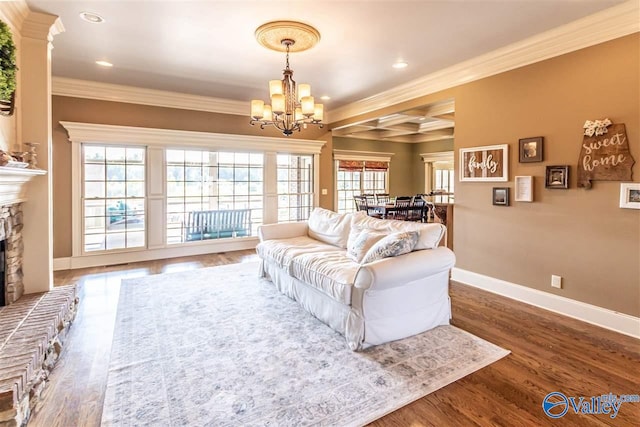 living area with ornamental molding, a fireplace with raised hearth, baseboards, and wood finished floors