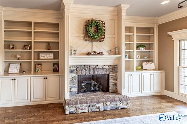 sitting room with a fireplace, ornamental molding, dark wood finished floors, and built in features