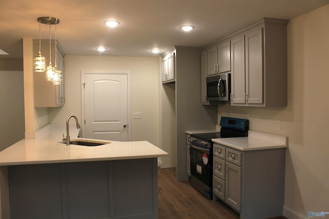 kitchen with a peninsula, gray cabinetry, dark wood-type flooring, appliances with stainless steel finishes, and a sink