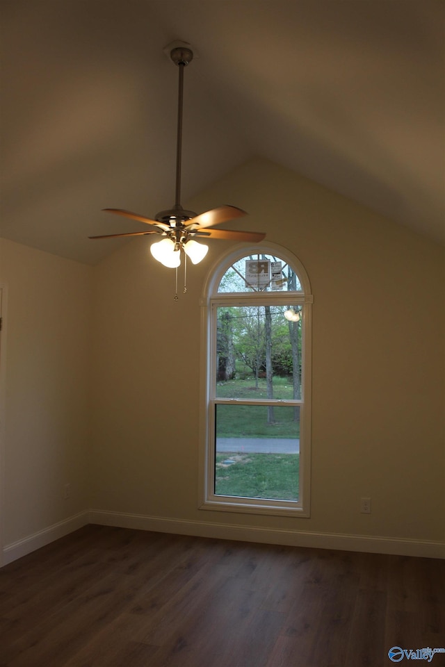 empty room with baseboards, a ceiling fan, vaulted ceiling, and dark wood finished floors