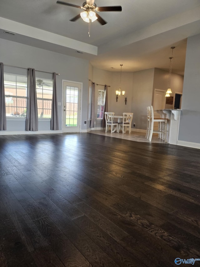 unfurnished living room featuring dark hardwood / wood-style floors and ceiling fan with notable chandelier