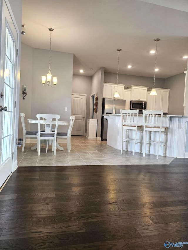 kitchen featuring stainless steel appliances, a kitchen breakfast bar, light hardwood / wood-style floors, decorative light fixtures, and white cabinets