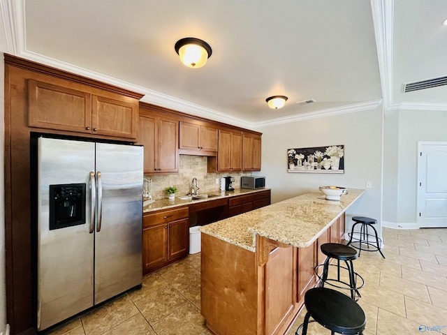 kitchen with sink, decorative backsplash, appliances with stainless steel finishes, a kitchen island, and a kitchen bar