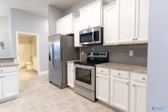 kitchen featuring backsplash, light stone countertops, white cabinetry, and stainless steel appliances