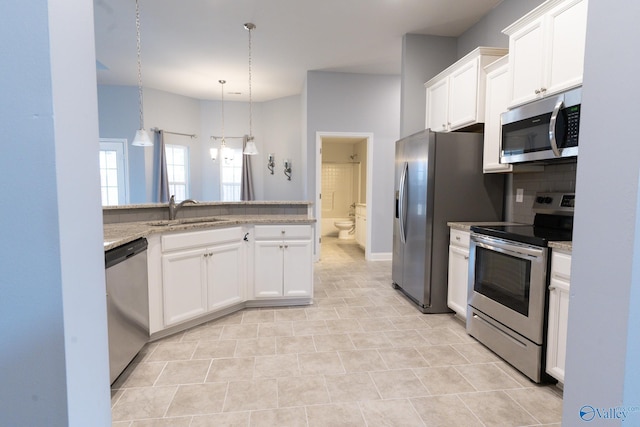 kitchen with white cabinets, stainless steel appliances, light stone counters, and sink