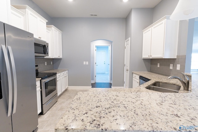 kitchen featuring sink, stainless steel appliances, tasteful backsplash, light stone counters, and white cabinets