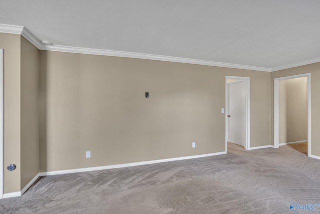 carpeted empty room featuring crown molding and baseboards