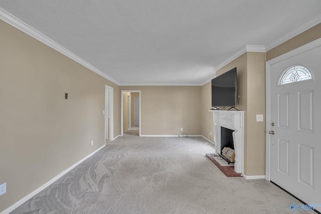 unfurnished living room with carpet floors, a fireplace with raised hearth, crown molding, and baseboards