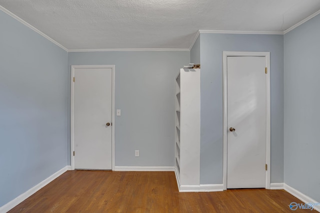 interior space featuring a textured ceiling, ornamental molding, wood finished floors, and baseboards