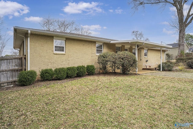 view of front of property with a front yard, brick siding, and fence