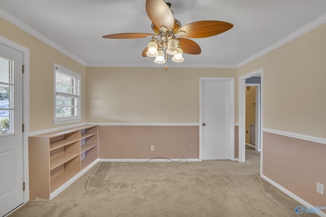 carpeted empty room with ceiling fan, baseboards, and crown molding