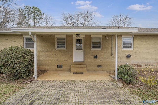 doorway to property with a shingled roof, crawl space, and brick siding