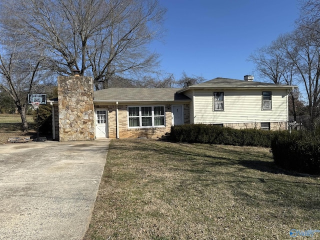 view of front facade featuring a front yard, driveway, and a chimney