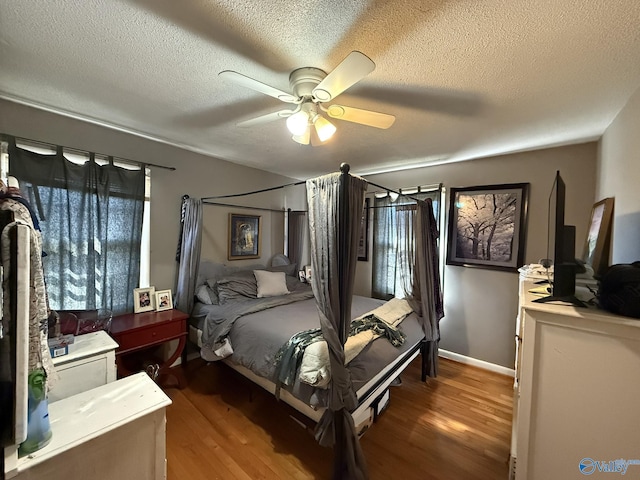 bedroom with baseboards, a textured ceiling, a ceiling fan, and wood finished floors