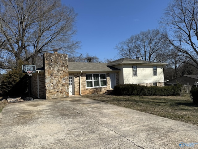 view of front of house with driveway, a front yard, a chimney, and brick siding