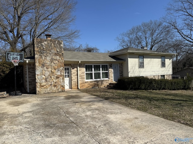 tri-level home with driveway, a chimney, and a front lawn