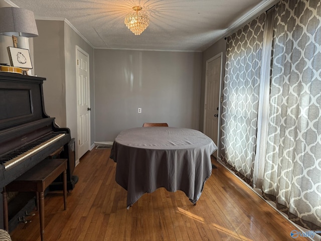 dining room with a textured ceiling, ornamental molding, and wood finished floors