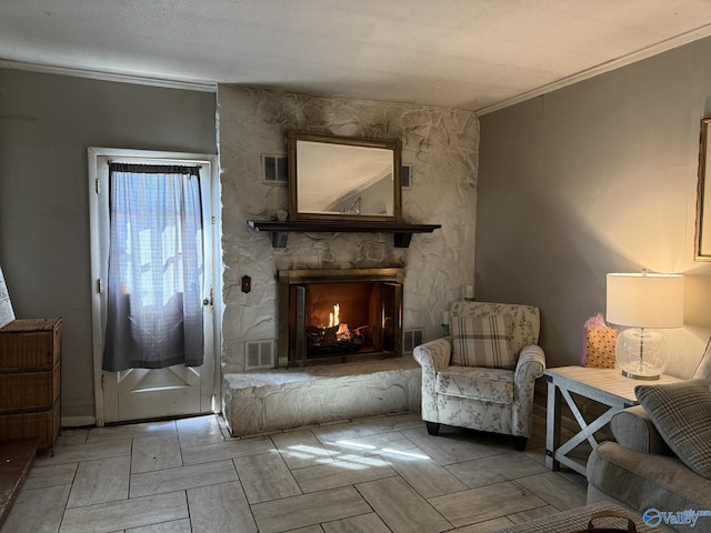 living area featuring ornamental molding, visible vents, and a fireplace