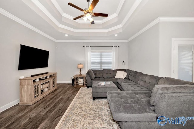 living room with dark wood-style floors, a tray ceiling, crown molding, and baseboards