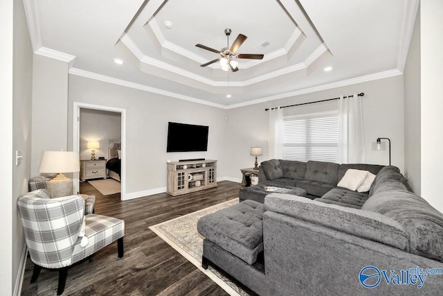 living area featuring crown molding, dark wood finished floors, a raised ceiling, a ceiling fan, and baseboards