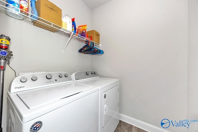 laundry room with laundry area, baseboards, wood finished floors, and washing machine and clothes dryer