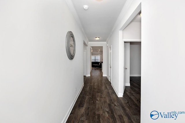 corridor with dark wood-style floors, baseboards, and ornamental molding