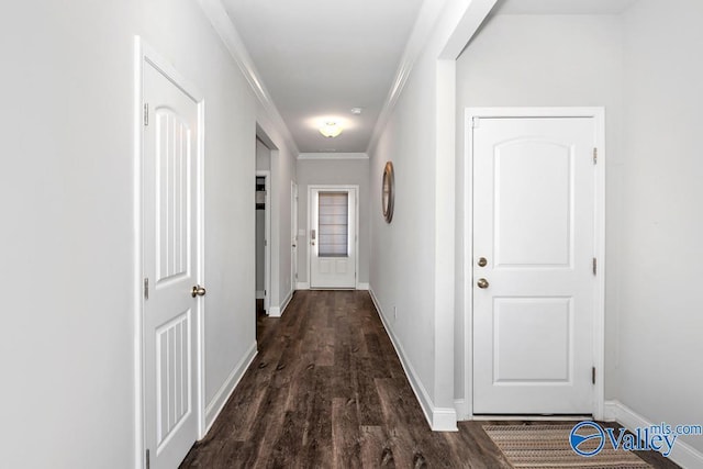 corridor with dark wood-type flooring, ornamental molding, and baseboards