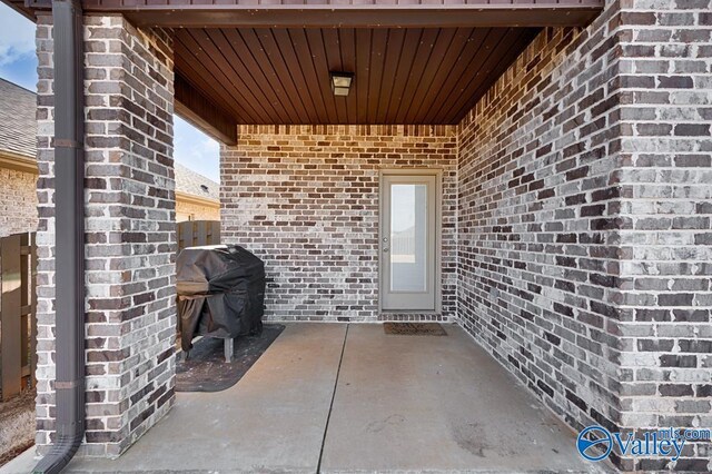 property entrance with brick siding and a patio