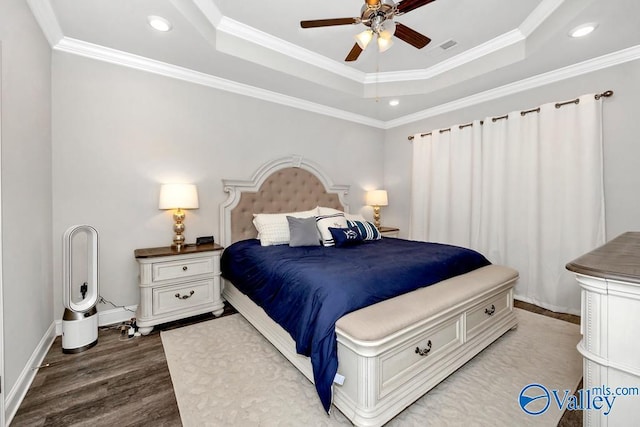 bedroom with ornamental molding, wood finished floors, a raised ceiling, and baseboards