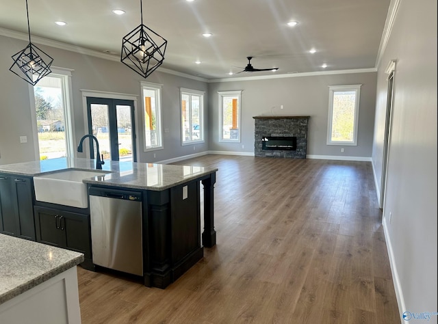 kitchen featuring hanging light fixtures, dishwasher, and light stone countertops