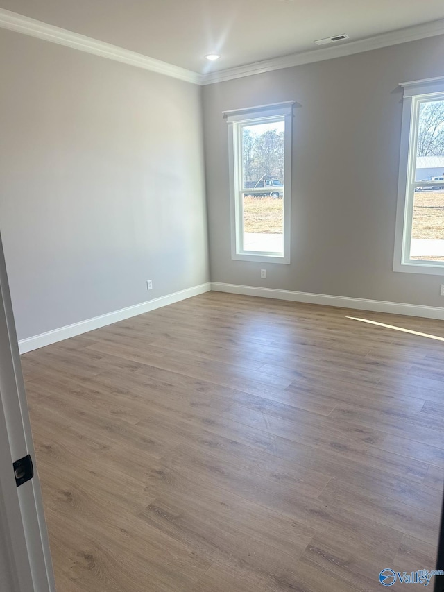 empty room with crown molding, a healthy amount of sunlight, and hardwood / wood-style floors