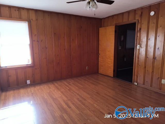 unfurnished room with ceiling fan, wood walls, and hardwood / wood-style flooring