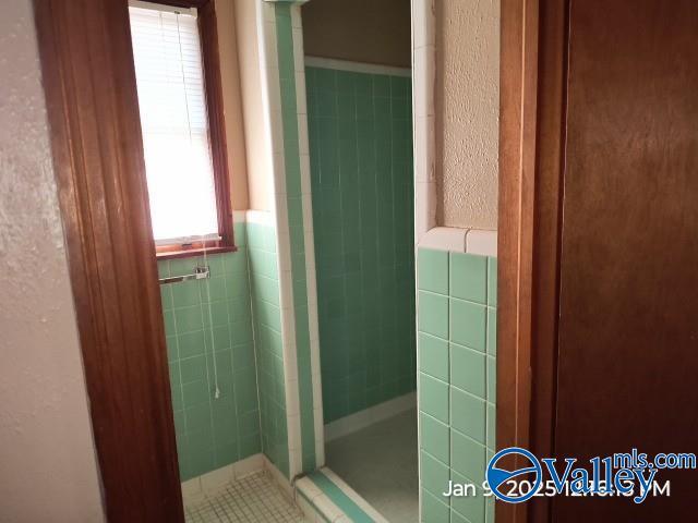 bathroom featuring tiled shower and tile walls