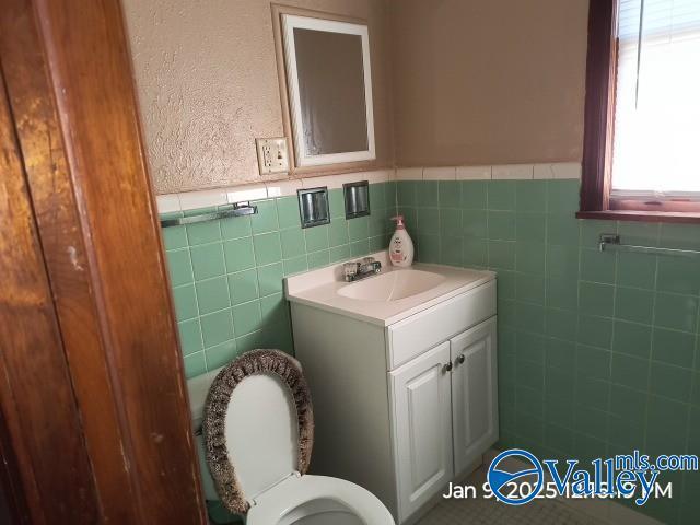 bathroom with vanity, toilet, and tile walls